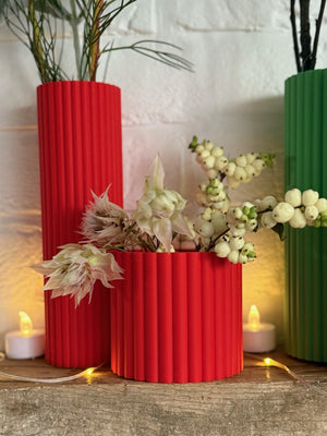 Close-up of red fluted Curve Vases with white berries and protea flowers