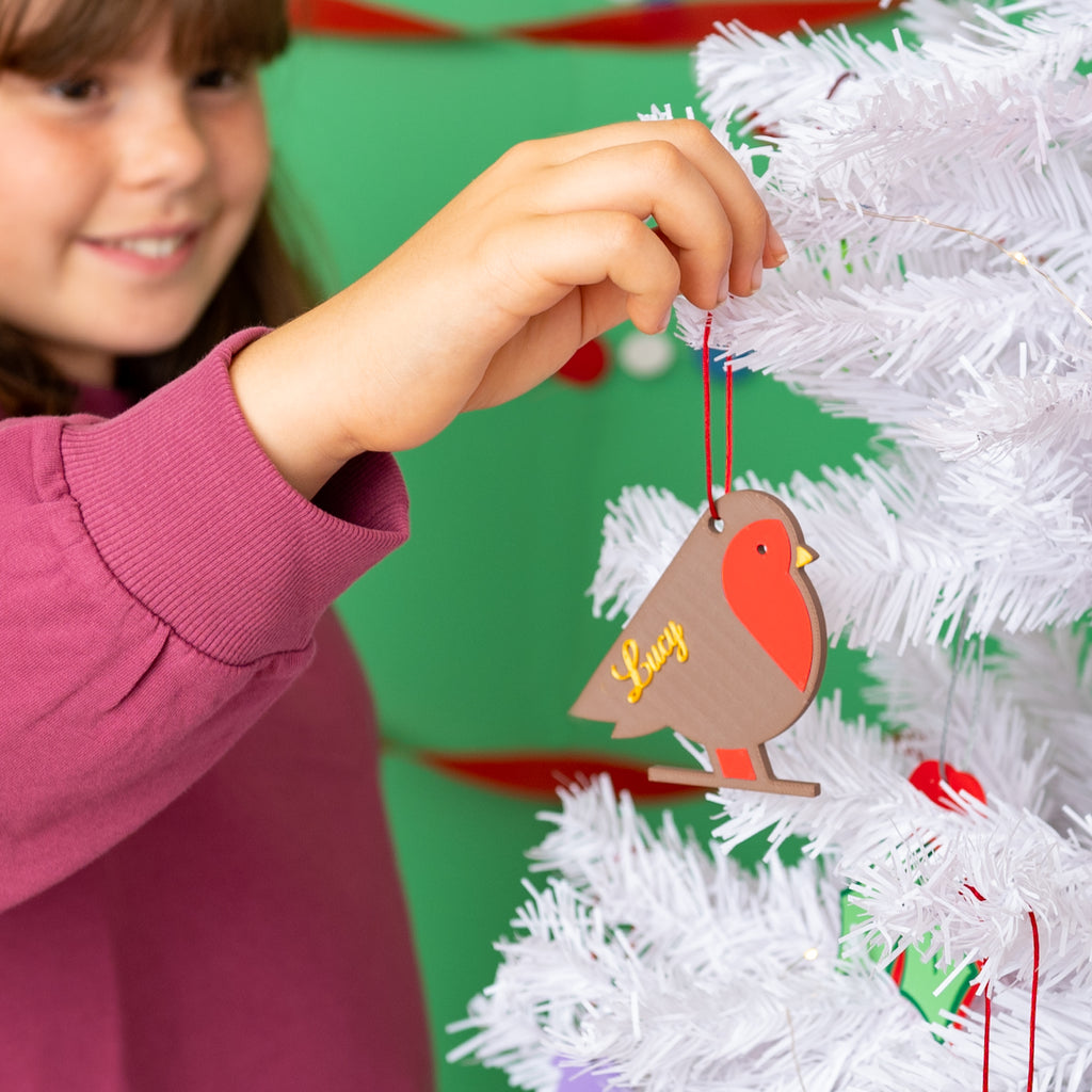 decorating the christmas tree with a robin bauble which is personalised with the name lucy in gold